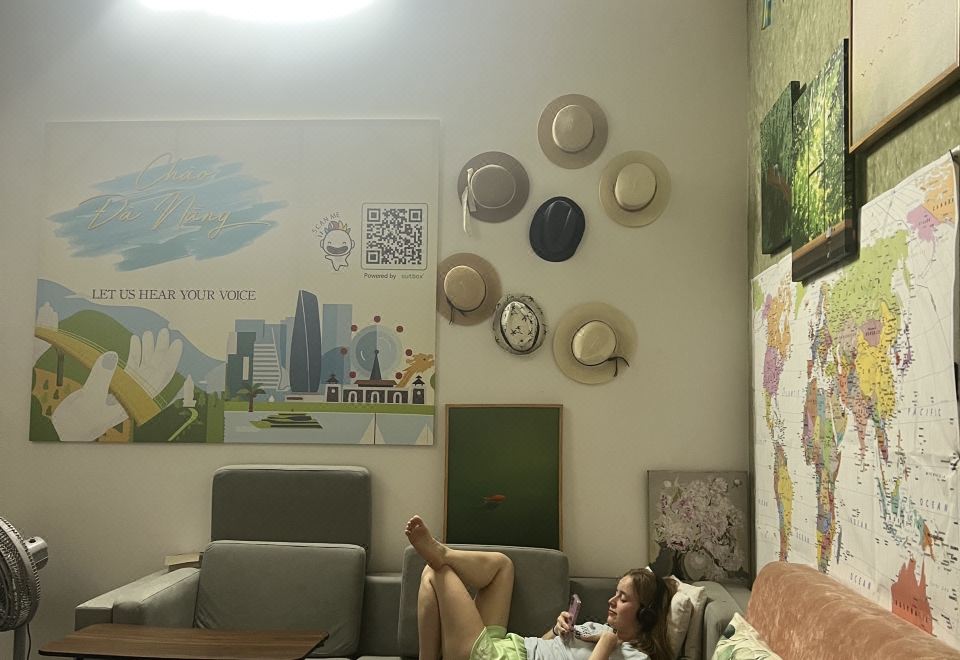A common room corner with a sofa, world map and decorative hats on the wall