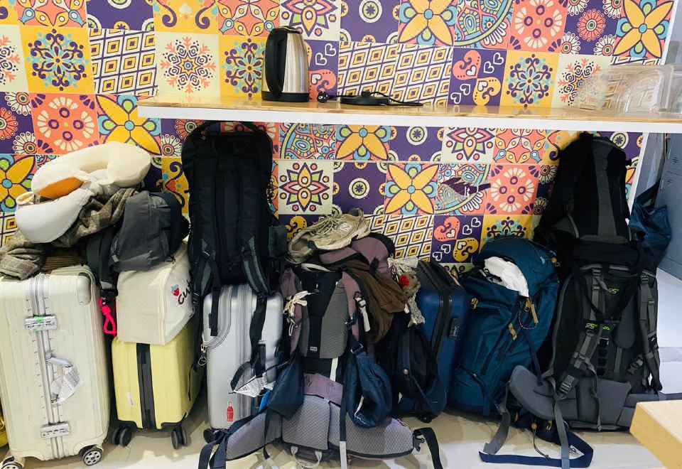 Luggage storage area with backpacks and suitcases against a tiled wall