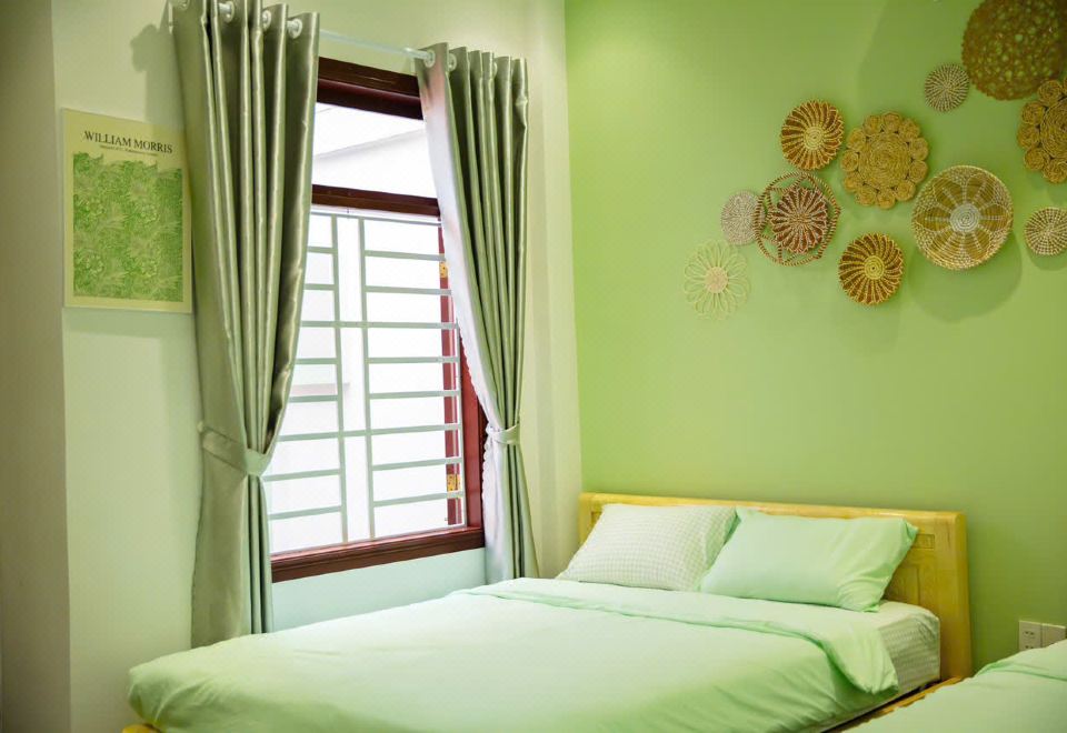 A single dorm bed with light green linen, air conditioning and a curtained window